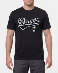 A model wears the STRAUSS Artwork T-Shirt e.s.e:pic in black with work pants and work boots in a studio product scene