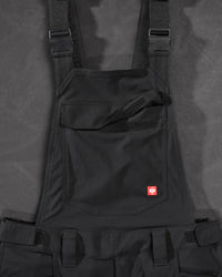 Close-up of black STRAUSS Stretch Ripstop Cargo Work Bib Overall e.s.taktik seam, hardware, and workwear details