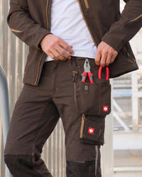 Large chestnut STRAUSS tool bag worn on matching work pants, with red-handled pliers in the pockets.