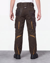 A person shown from the back wearing dark brown cargo work pants with tan contrast panels and black shoes, standing against a plain light gray studio background.
