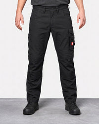 A person wearing black cargo pants with multiple utility pockets and black work boots, standing against a light gray studio background.