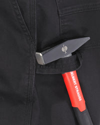 Close-up of a black tool pouch on dark workwear pants, holding a red and black hand tool with a silver metal head. The brand name 'ENGELBERT STAUSS' is visible on the tool handle.