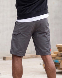 A person wearing dark gray cargo shorts, shown from the back. The shorts feature a white undershirt peeking out at the hem, a black sweatshirt on top, and a small red logo on the lower right leg.