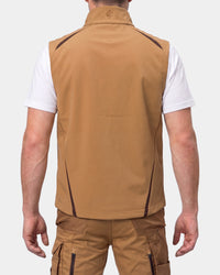 A man shown from the back wearing a tan sleeveless zip-front vest over a white t-shirt and tan cargo pants, against a light gray studio background.
