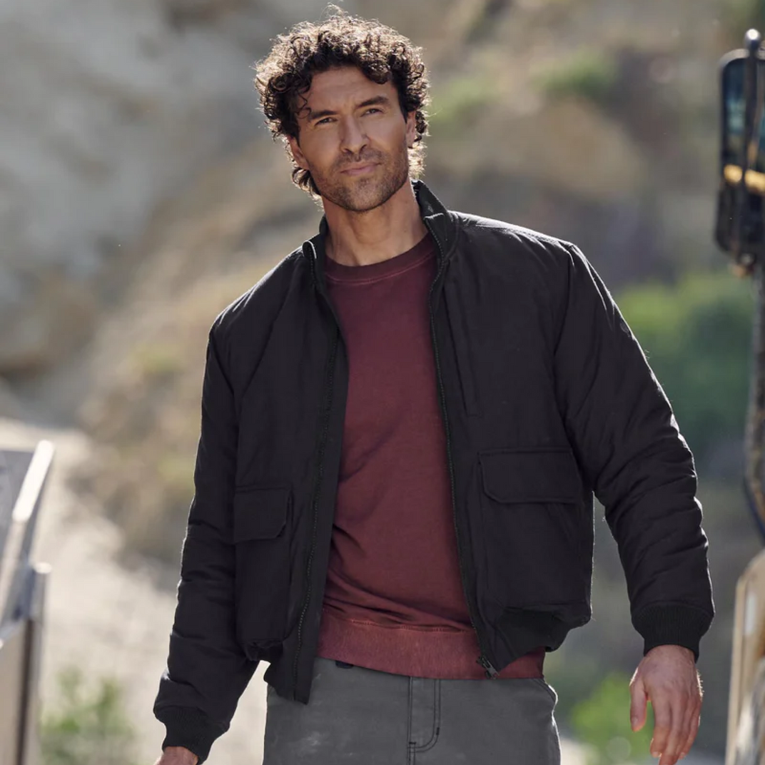 Man wearing a black jacket over a red shirt outdoors