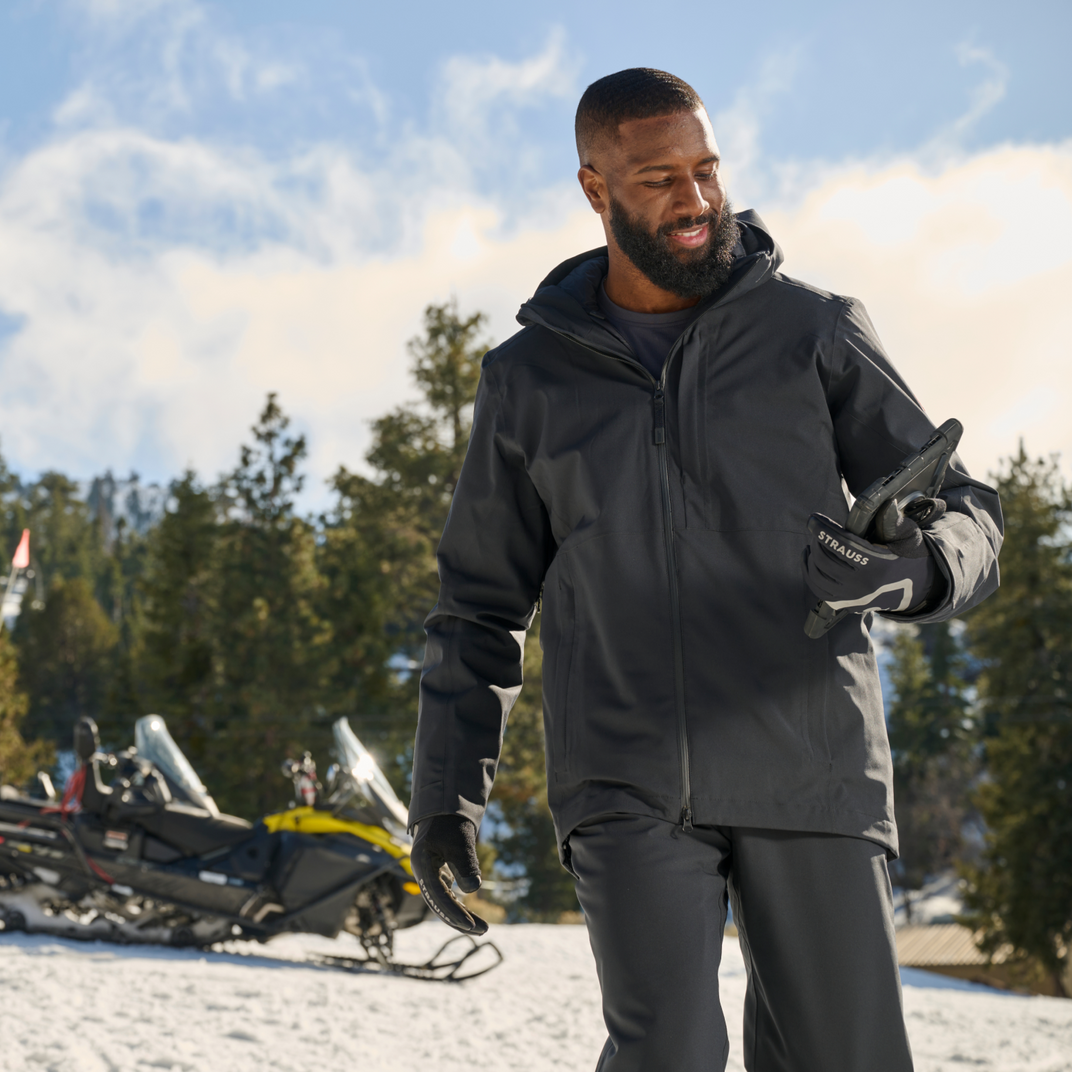 Man in winter clothing standing in a snowy landscape with trees and a clear sky.