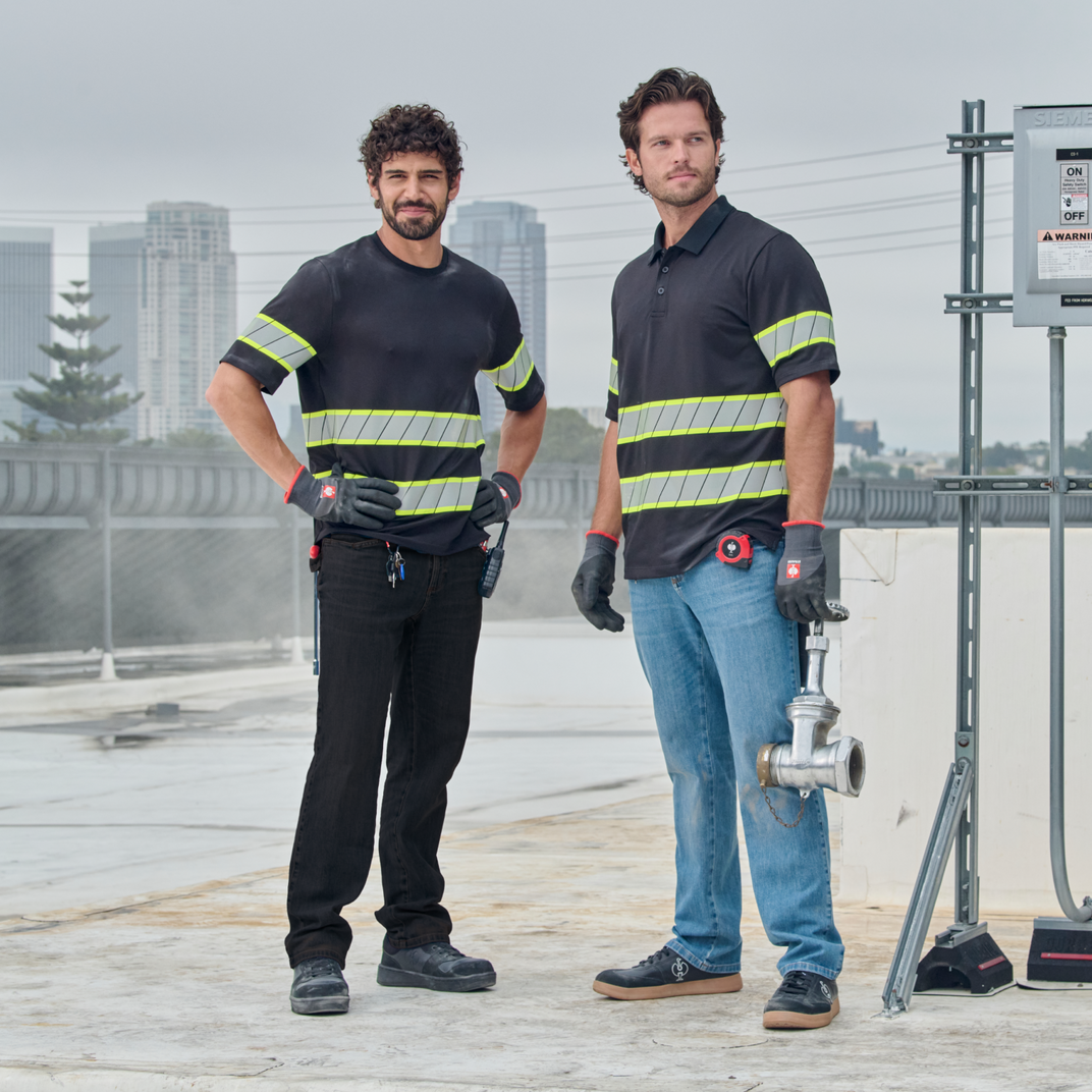 Two men on a rooftop wearing black and blue jeans and a high-vis T-Shirt and Polo Shirt