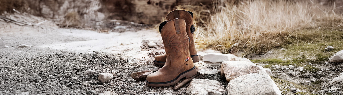 A pair of Doonan Boots standing in an outdoor environment on gravel.
