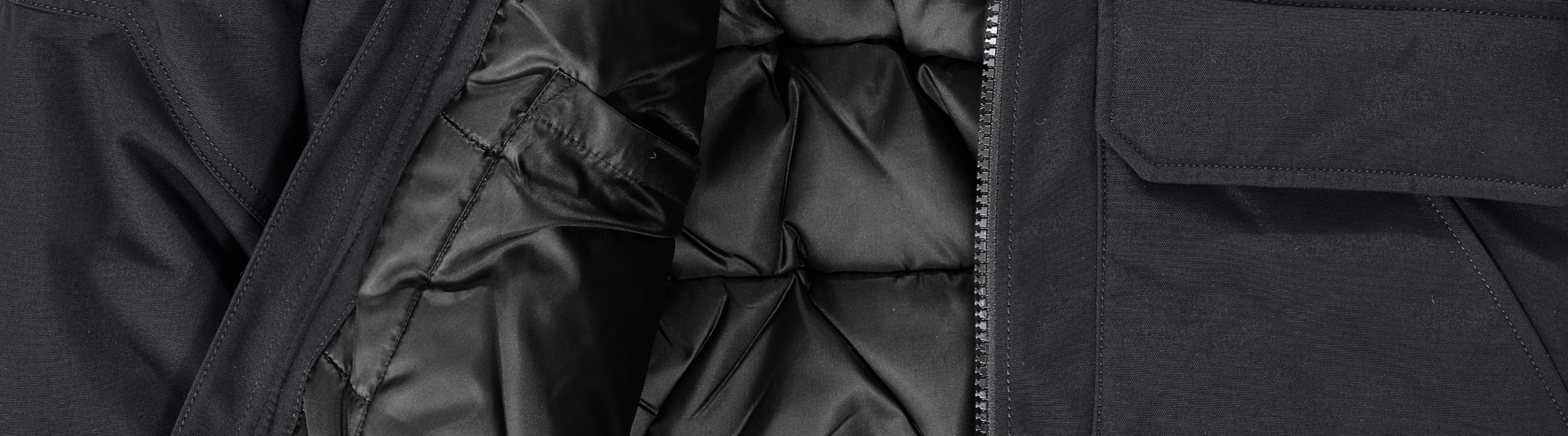 Close-up of the inside of a black padded jacket, showing quilted lining, smooth inner fabric, and part of a zippered opening.