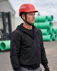 A bright red STRAUSS Baseball Style Hard Hat with a visor on a model as seen from the side. 