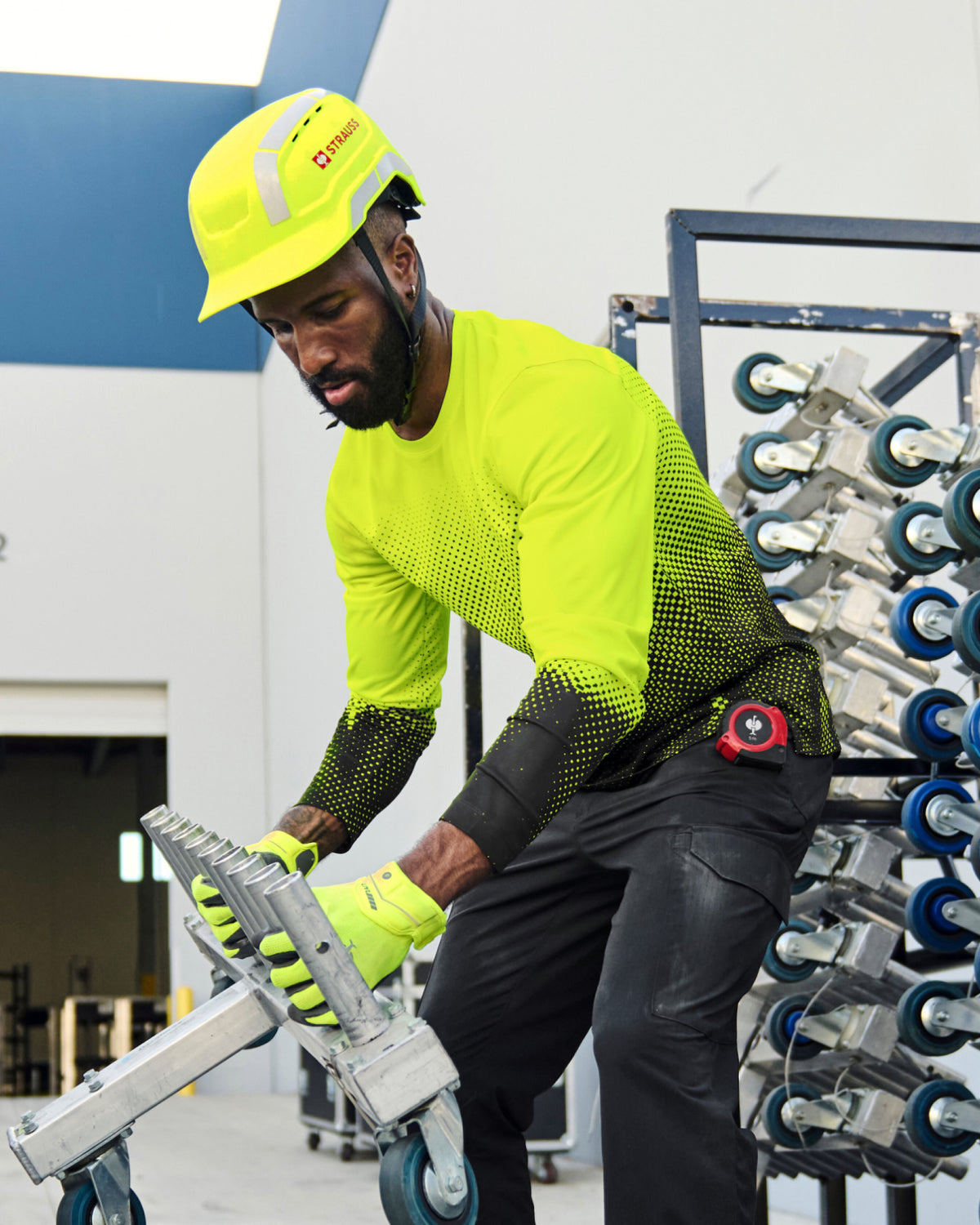 A bright yellow STRAUSS Baseball Style Hard Hat with a visor on a model working in a factory. 
