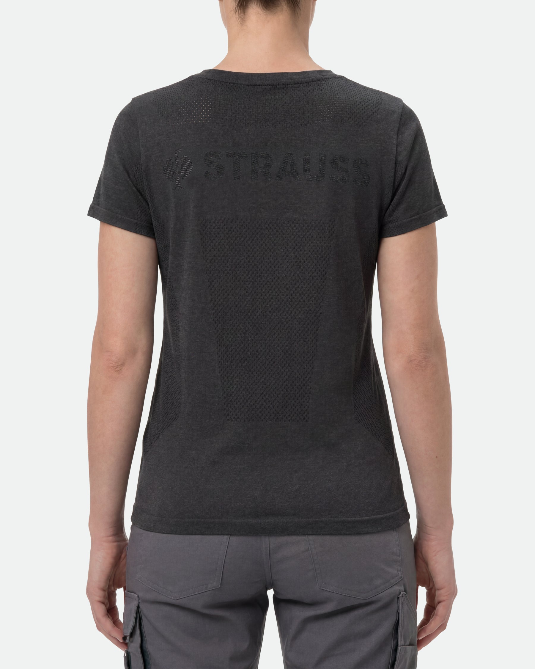 A woman wears the Women's STRAUSS Seamless Tee e.s.trail pure in black melange with work gloves and work pants, showing the shirt fit