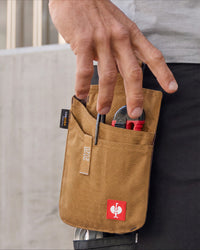 Hand reaching into a small almond brown STRAUSS tool bag holding pliers at the hip.