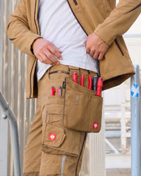 Large almond brown STRAUSS tool bag worn on matching work pants, with red-handled tools in its pockets.