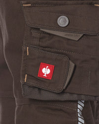 Close-up of dark brown canvas cargo pants showing a front utility pocket with a red square patch featuring a white stylized logo.