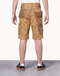A person shown from the back wearing tan cargo shorts with multiple flap pockets and zippered side pockets, paired with black-and-white sneakers against a plain studio background.