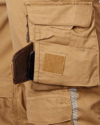 Close-up of a tan cargo pocket showing a side utility pocket containing a black smartphone, alongside a tan Velcro patch.