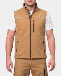 A man wearing a tan zip-up vest over a white t-shirt and matching tan cargo pants, shown from the neck down against a light gray studio background.