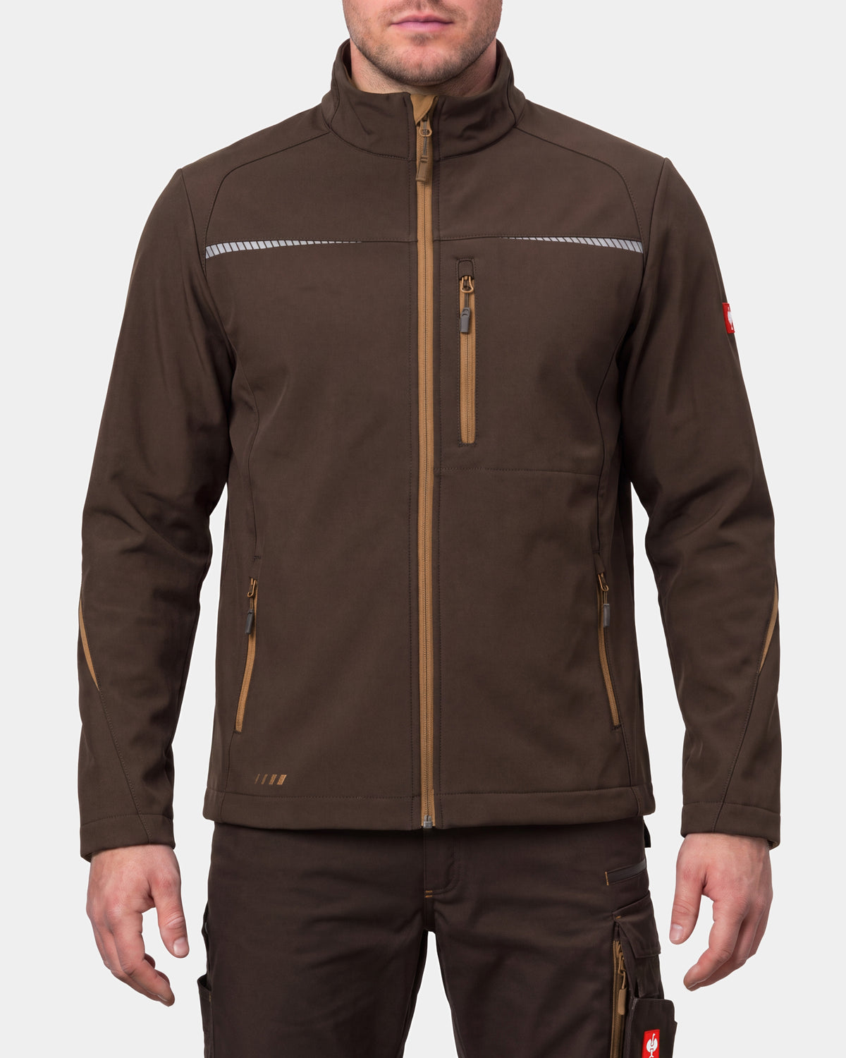 A man wearing a brown technical softshell jacket with tan zipper details and reflective chest stripes, paired with matching brown pants, against a light gray studio background.
