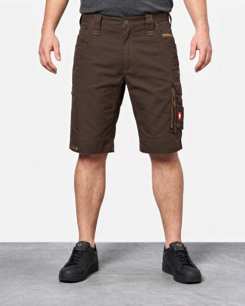 A person wearing dark brown cargo shorts with side utility pockets, paired with black sneakers, shown from the waist down against a light gray studio background.
