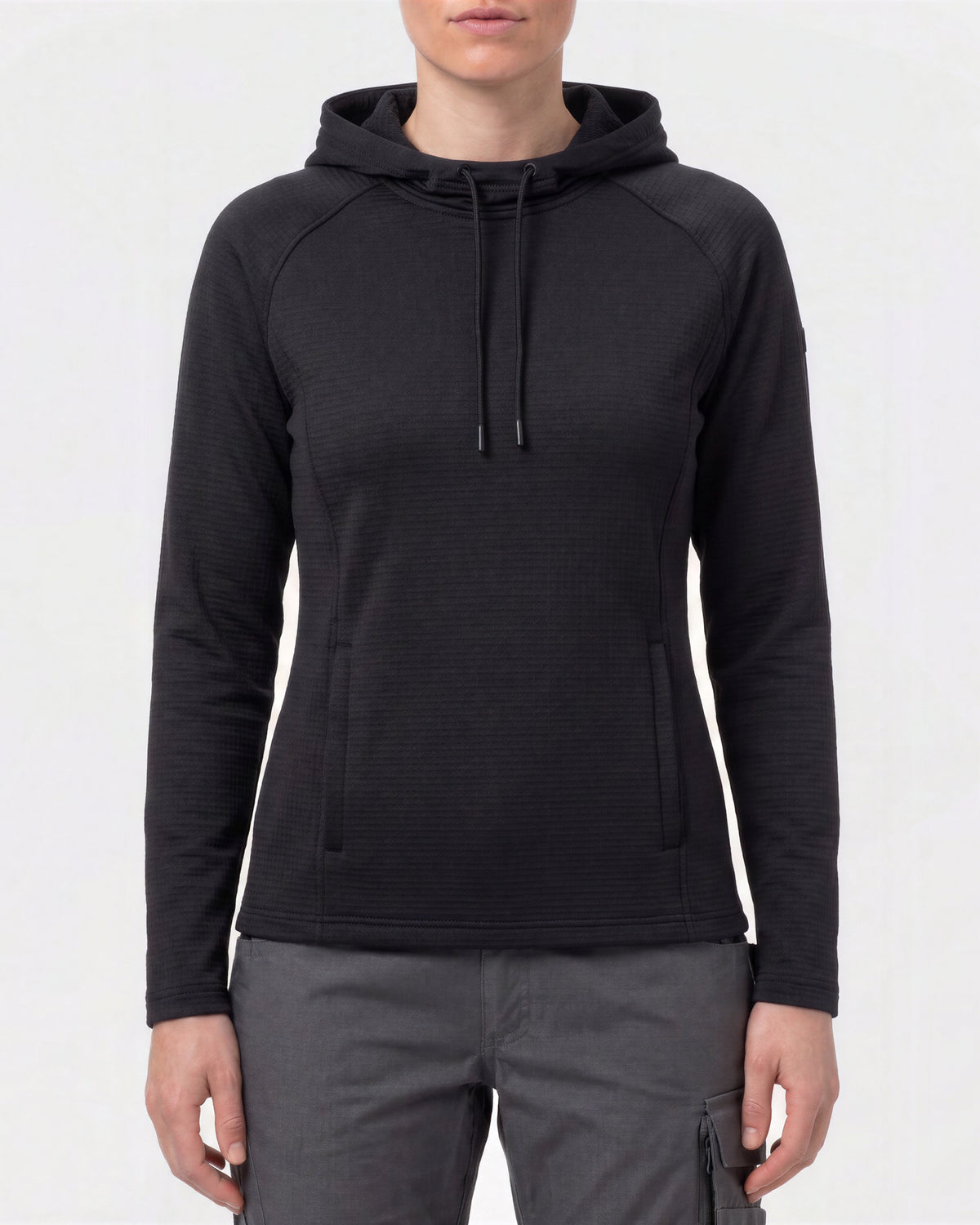 A woman wearing a black long-sleeve hooded pullover with a textured knit fabric, shown from the neck down against a light gray studio background.