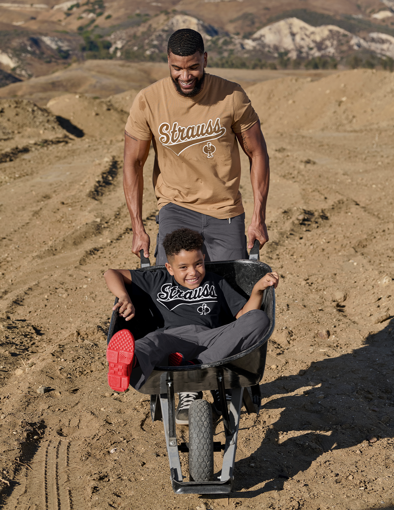 Two people wearing Strauss t-shirts in a desert setting