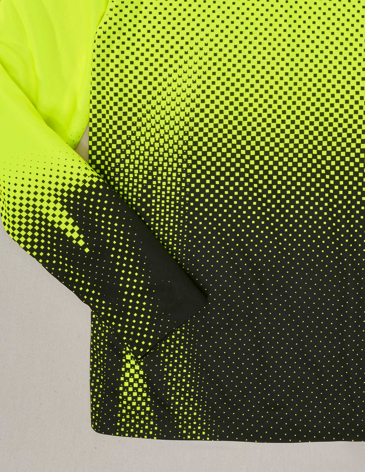 Close-up of a fabric with a gradient pattern transitioning from yellow to black on a gray background.