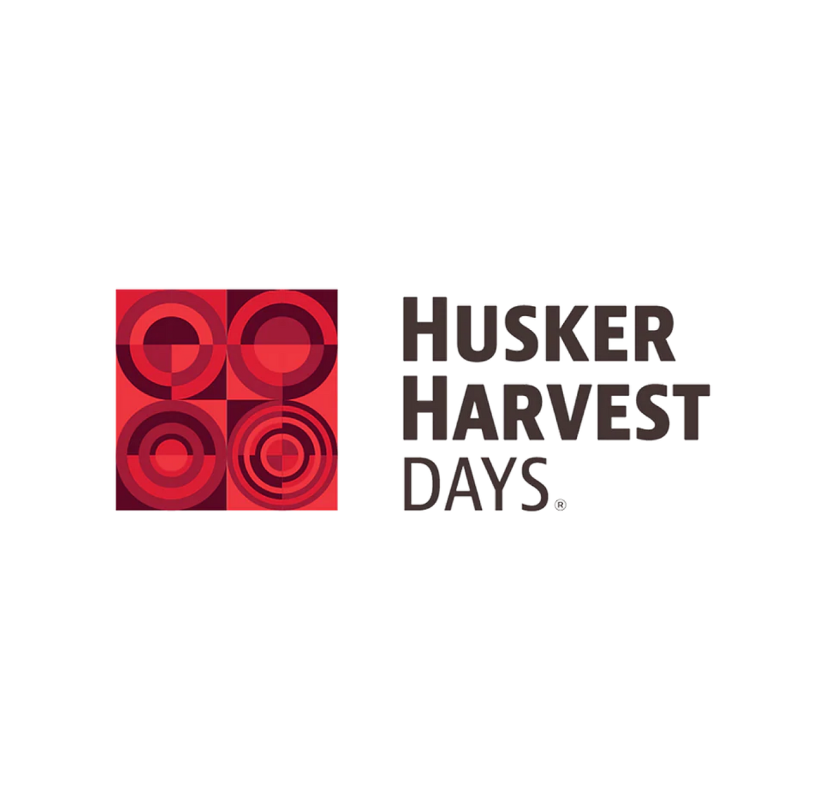 Logo with red geometric shapes on the left and the words Husker Harvest Days in bold black text on the right, all on a white background.