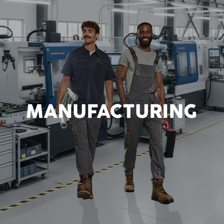 Two workers in a manufacturing setting with machinery in the background