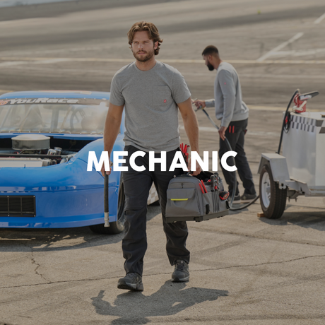Mechanic walking with tools near a blue race car on a track