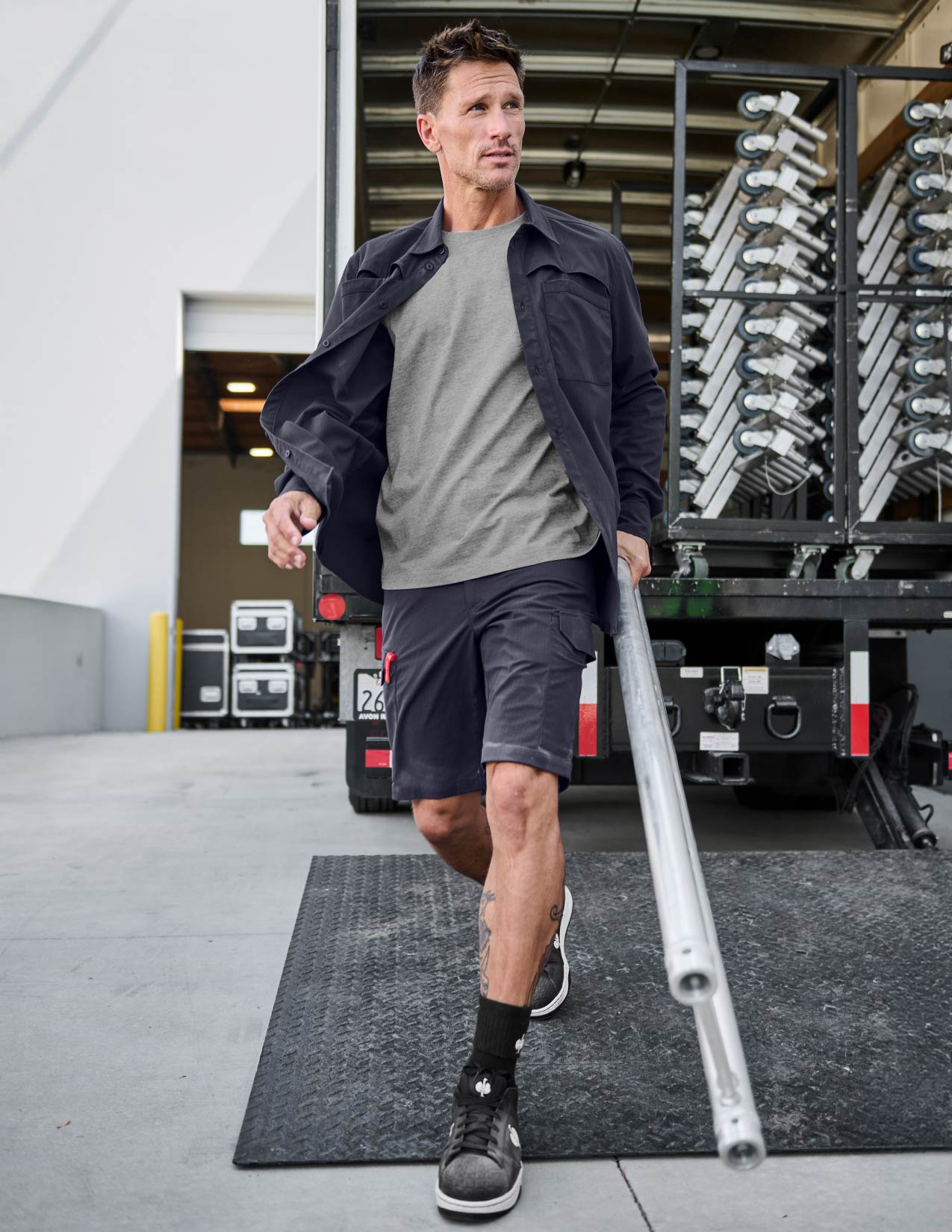 Man walking with a long metal rod in an industrial setting