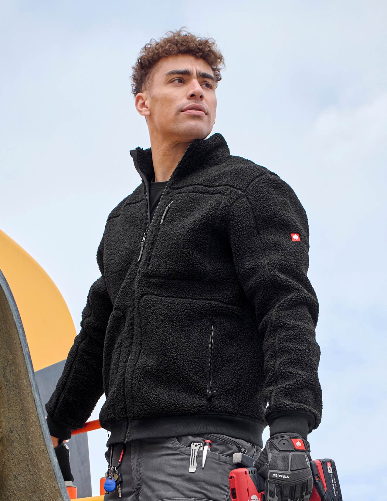 Man wearing a black fleece jacket with a visible brand logo, standing outdoors.