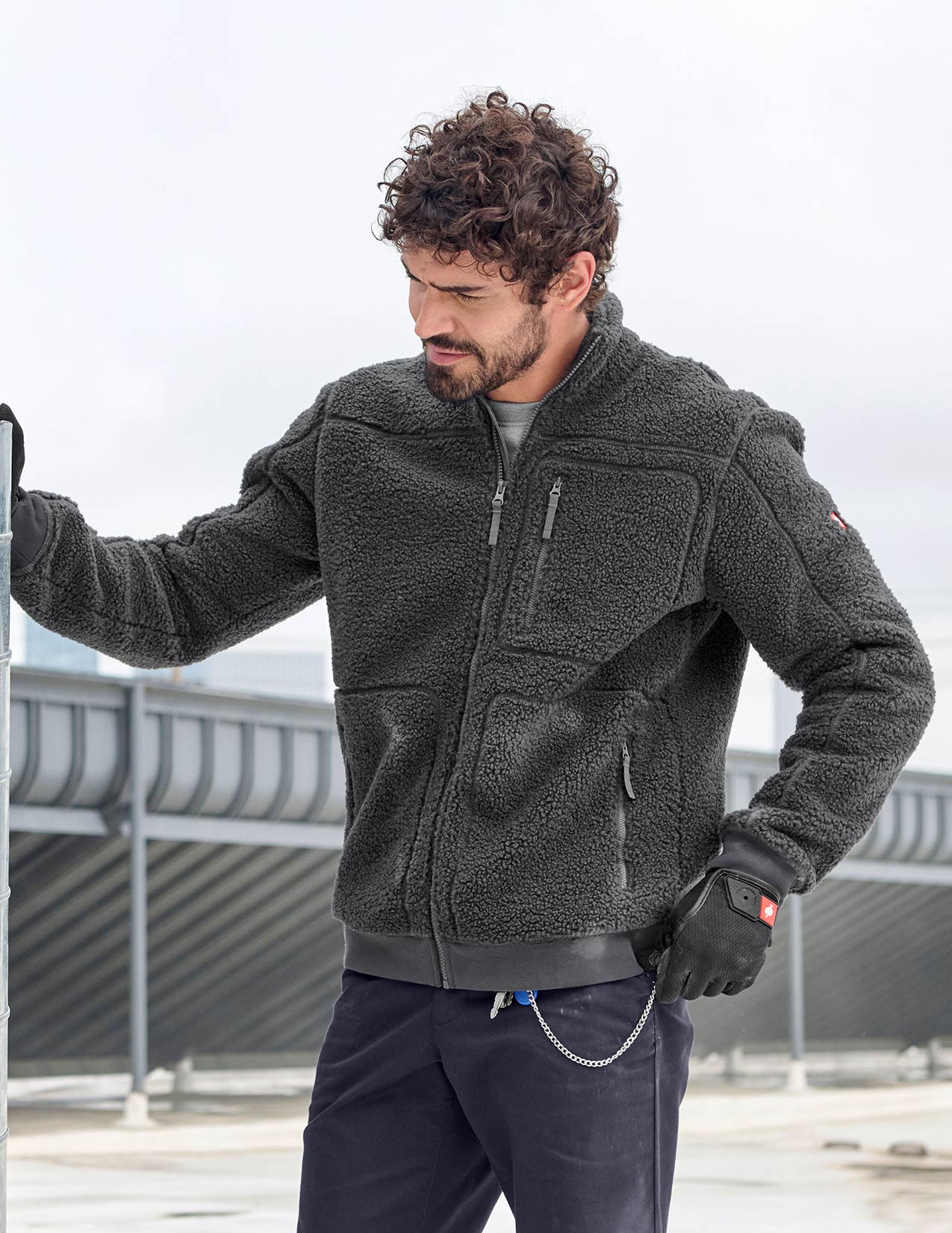 Man wearing a dark gray fleece jacket and gloves outdoors