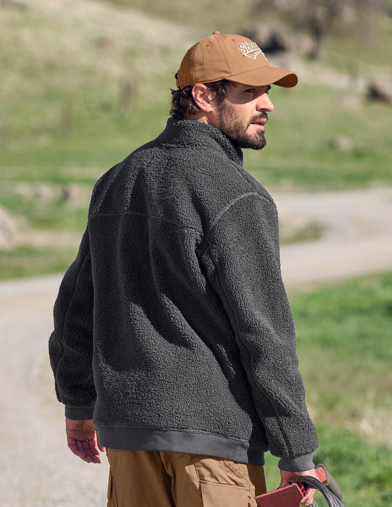 Man wearing a dark gray fleece jacket and brown cap outdoors