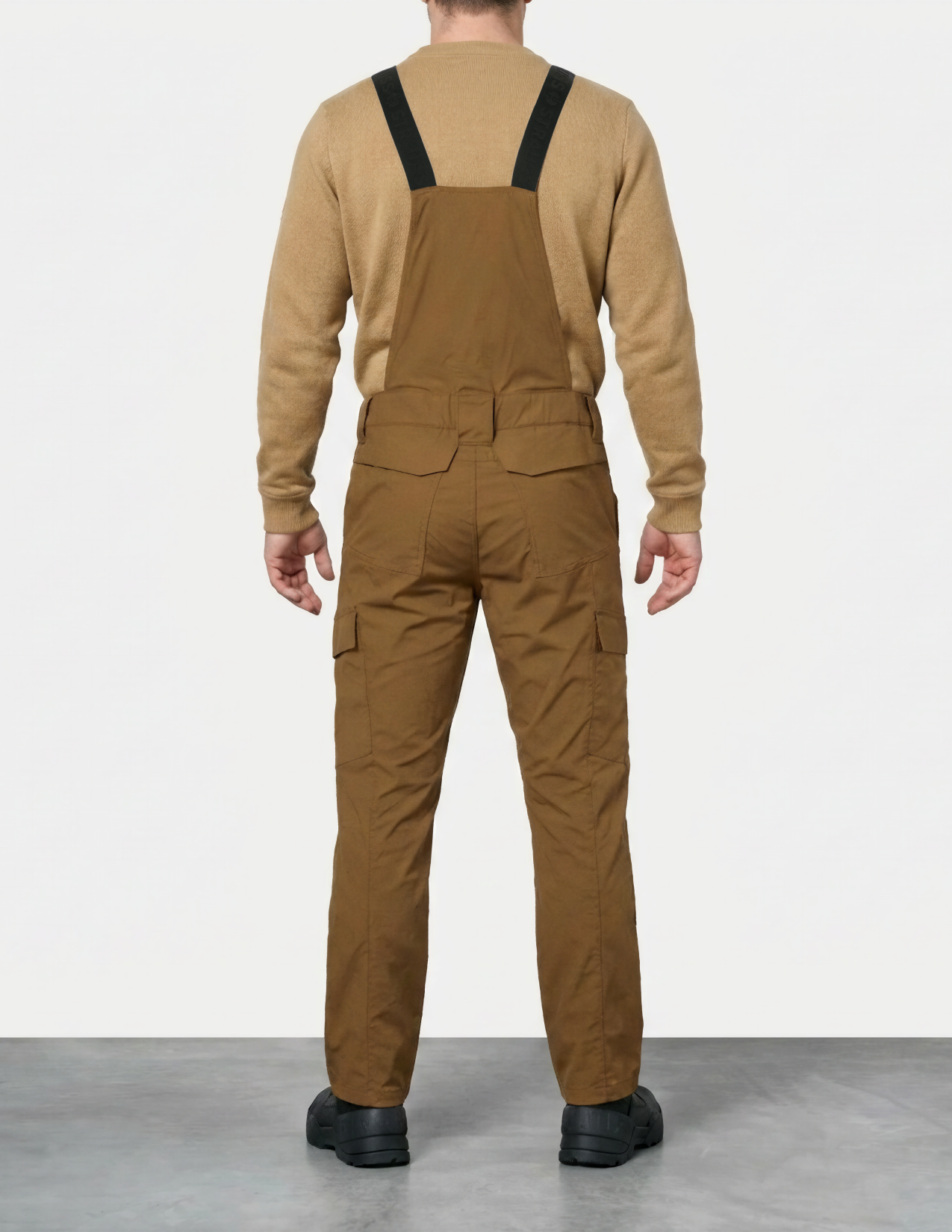 a man wearing almondbrown bib overalls on a white background
