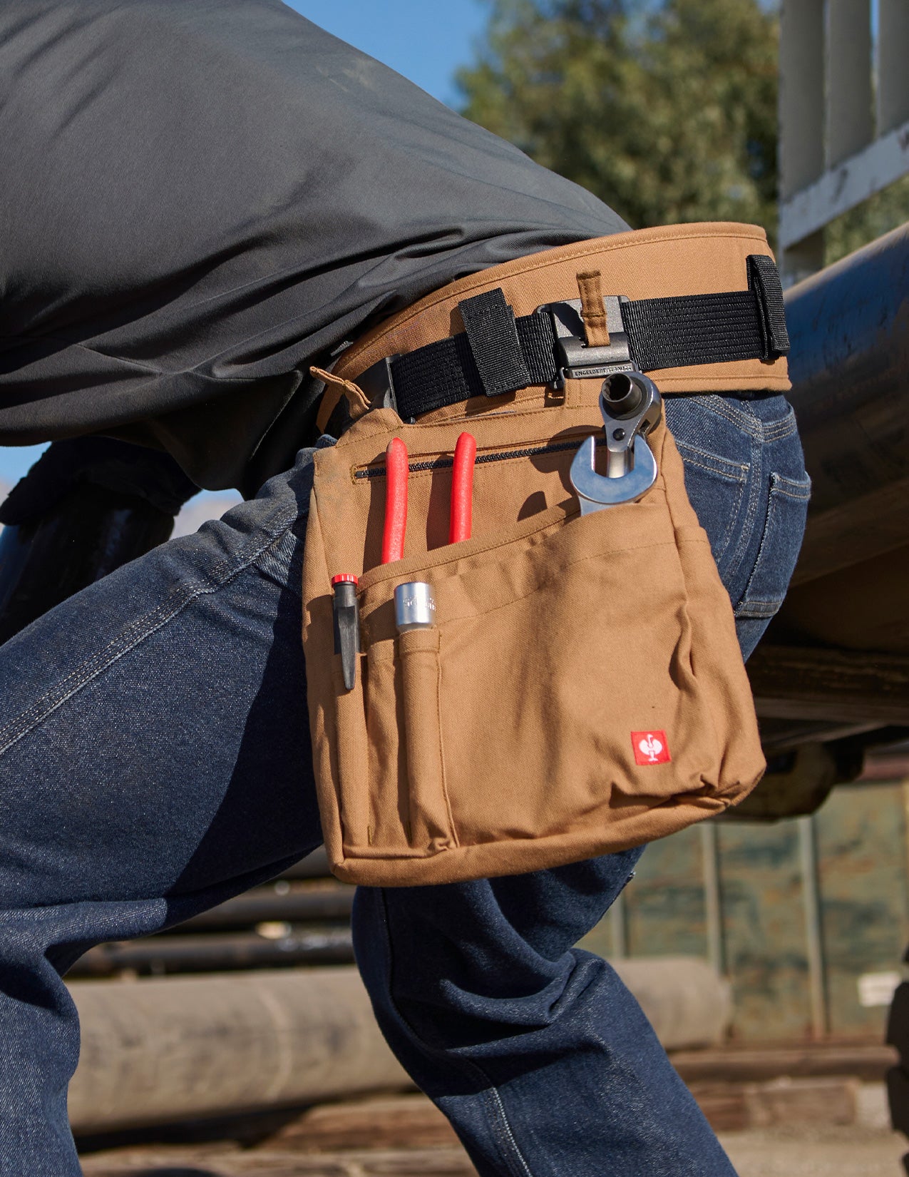 Man bending over with tool belt that has an attached bag filled with tools