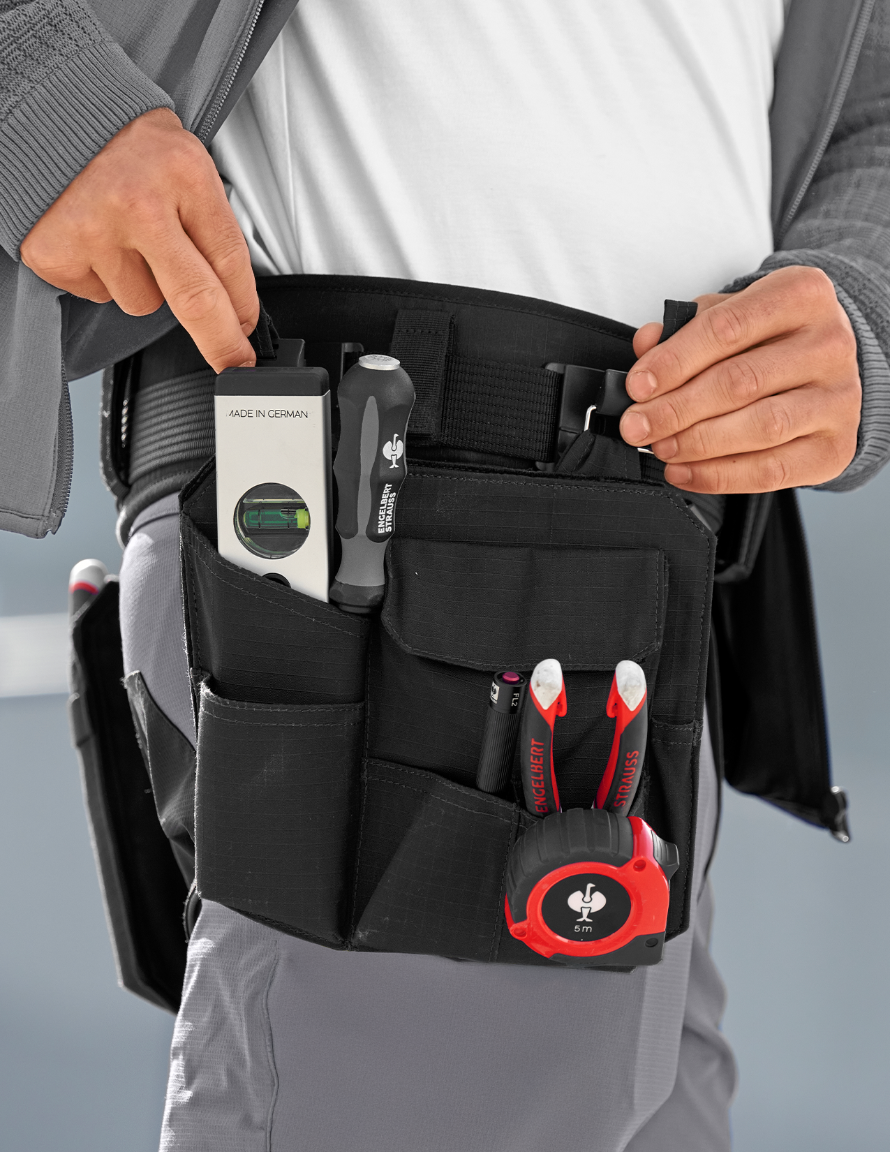 Man putting a tool bag on his tool belt