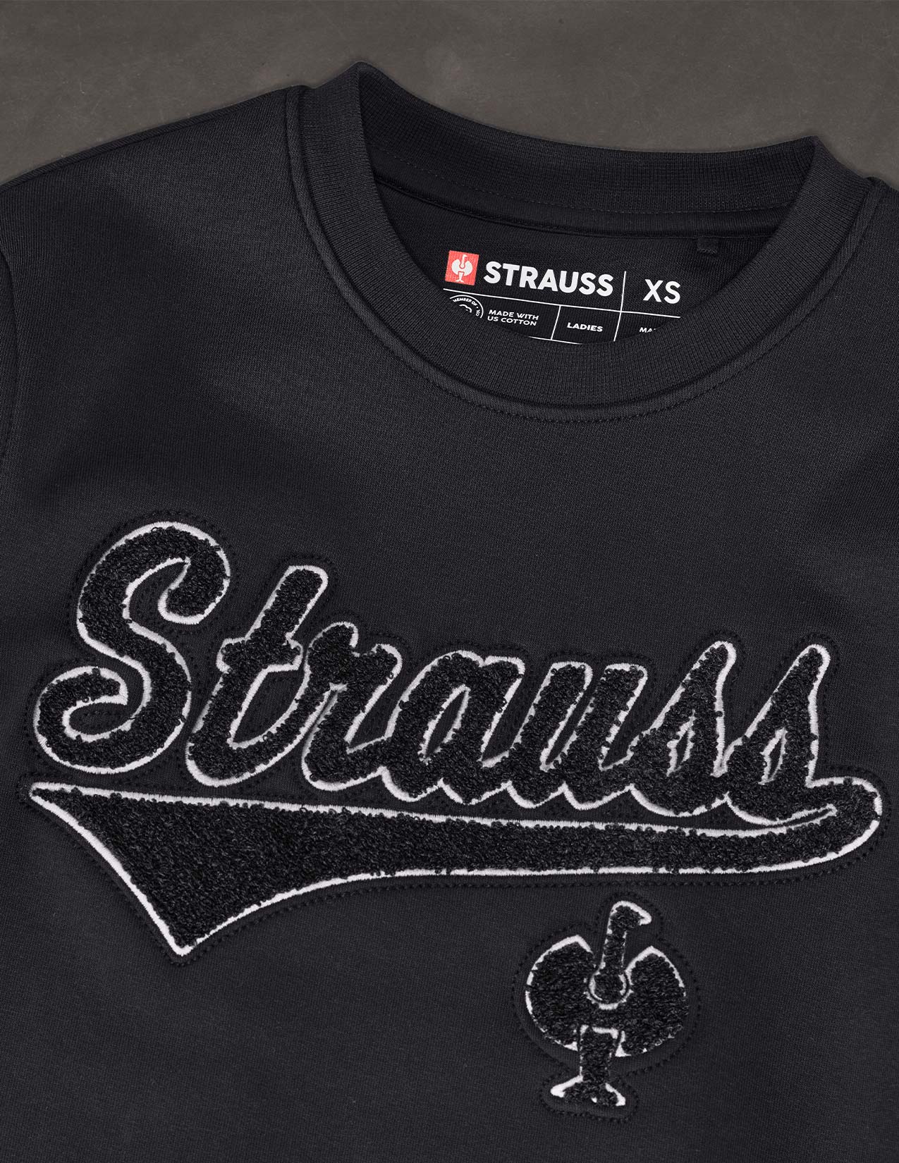 Black Sweatshirt with 'Strauss' branding and logo on a dark background