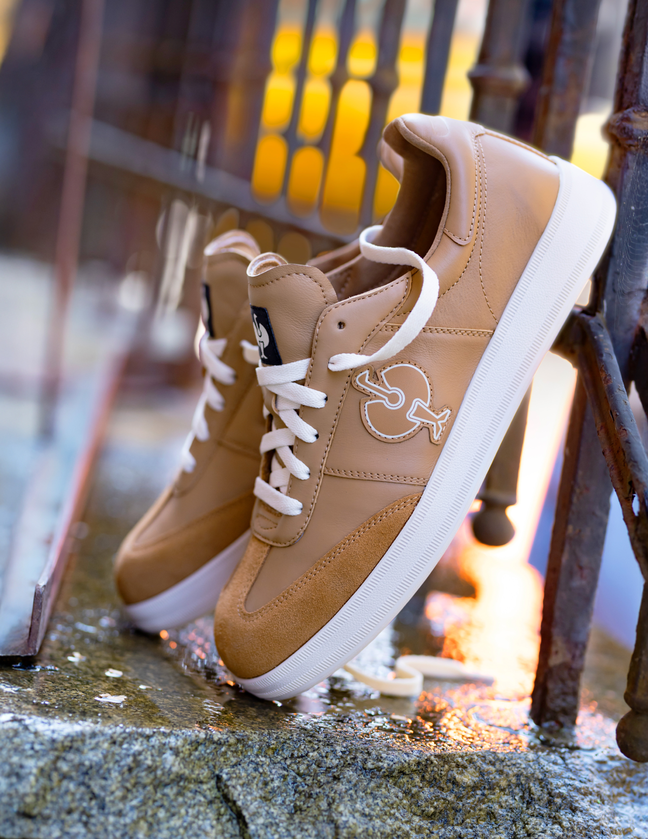 beige sneakers with white soles on a textured surface with blurred background