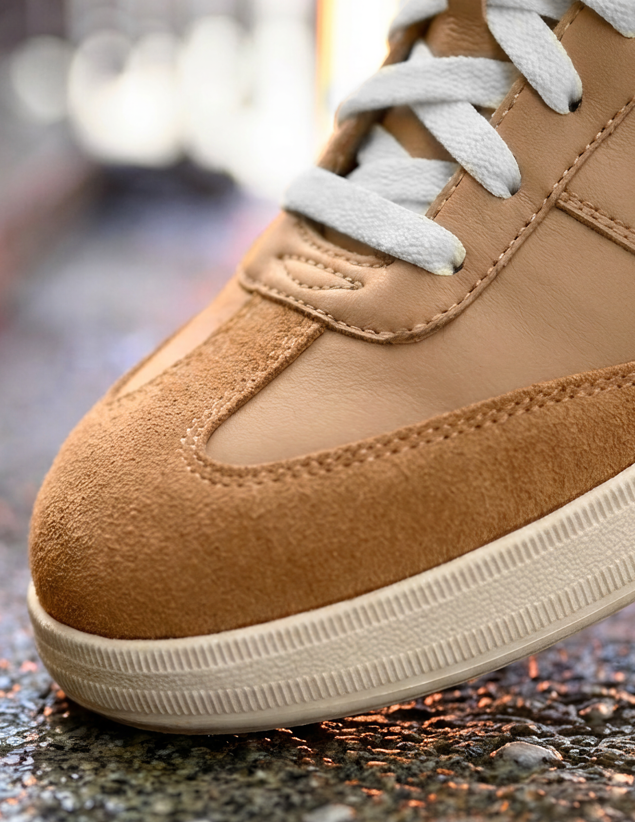 Close-up of a brown sneaker with white laces on a textured surface.