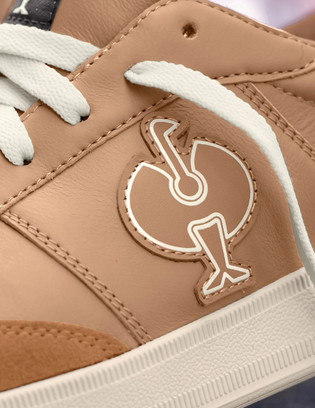 Close-up of a beige sneaker with a logo on the side