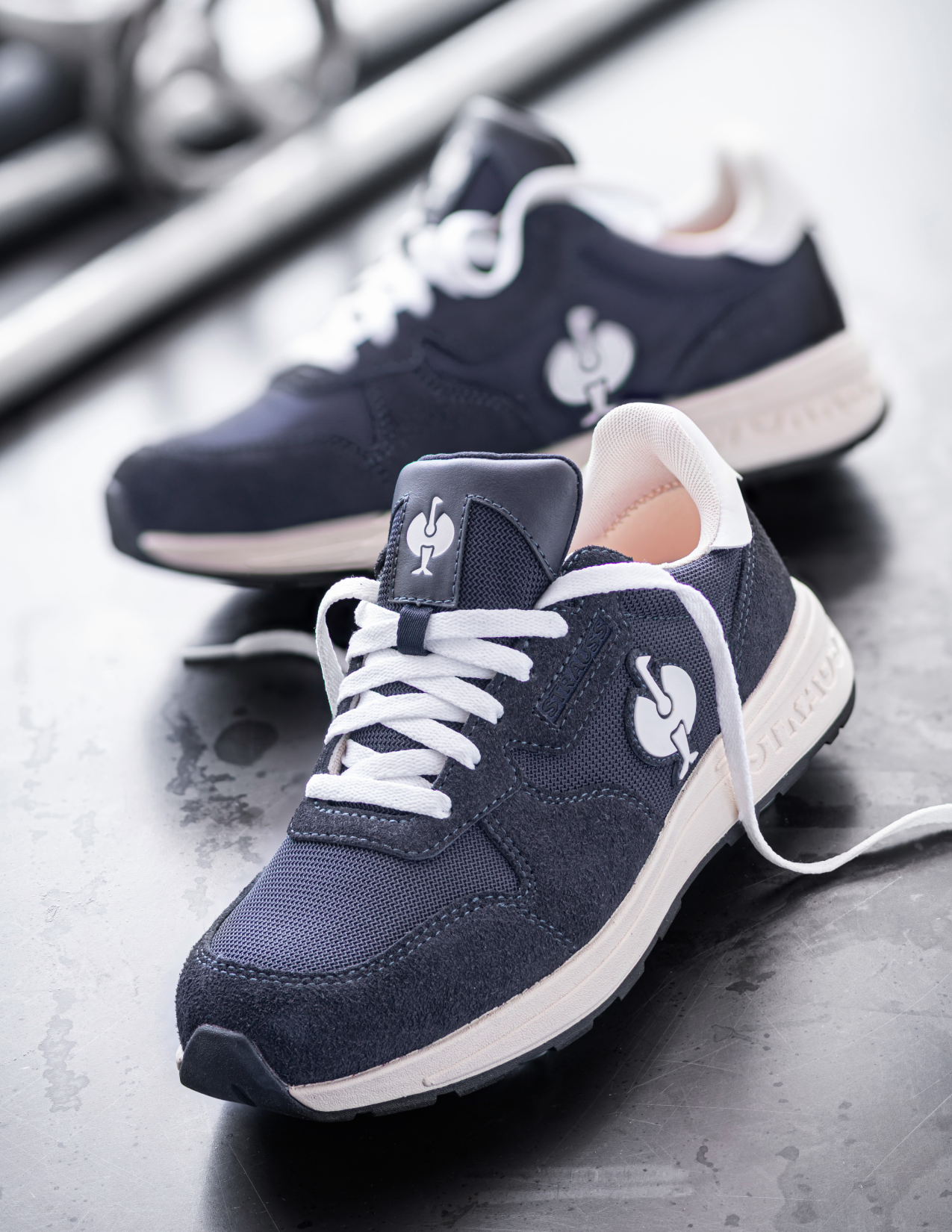 Navy blue sneakers with white soles on a dark surface