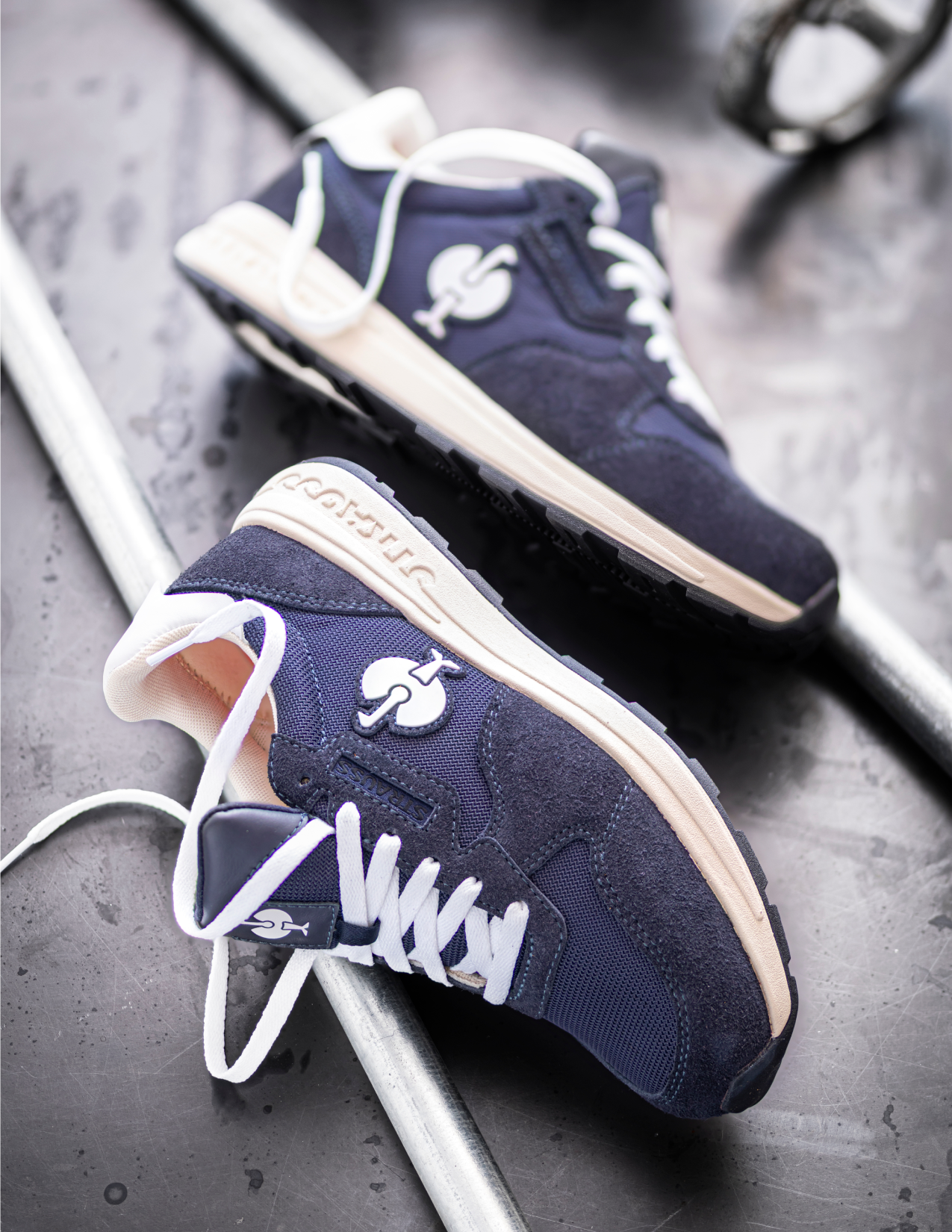 Navy blue sneakers with white soles on a metallic surface