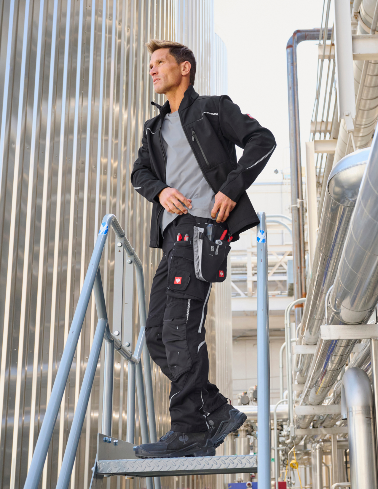Person in work attire standing on a ladder in an industrial setting