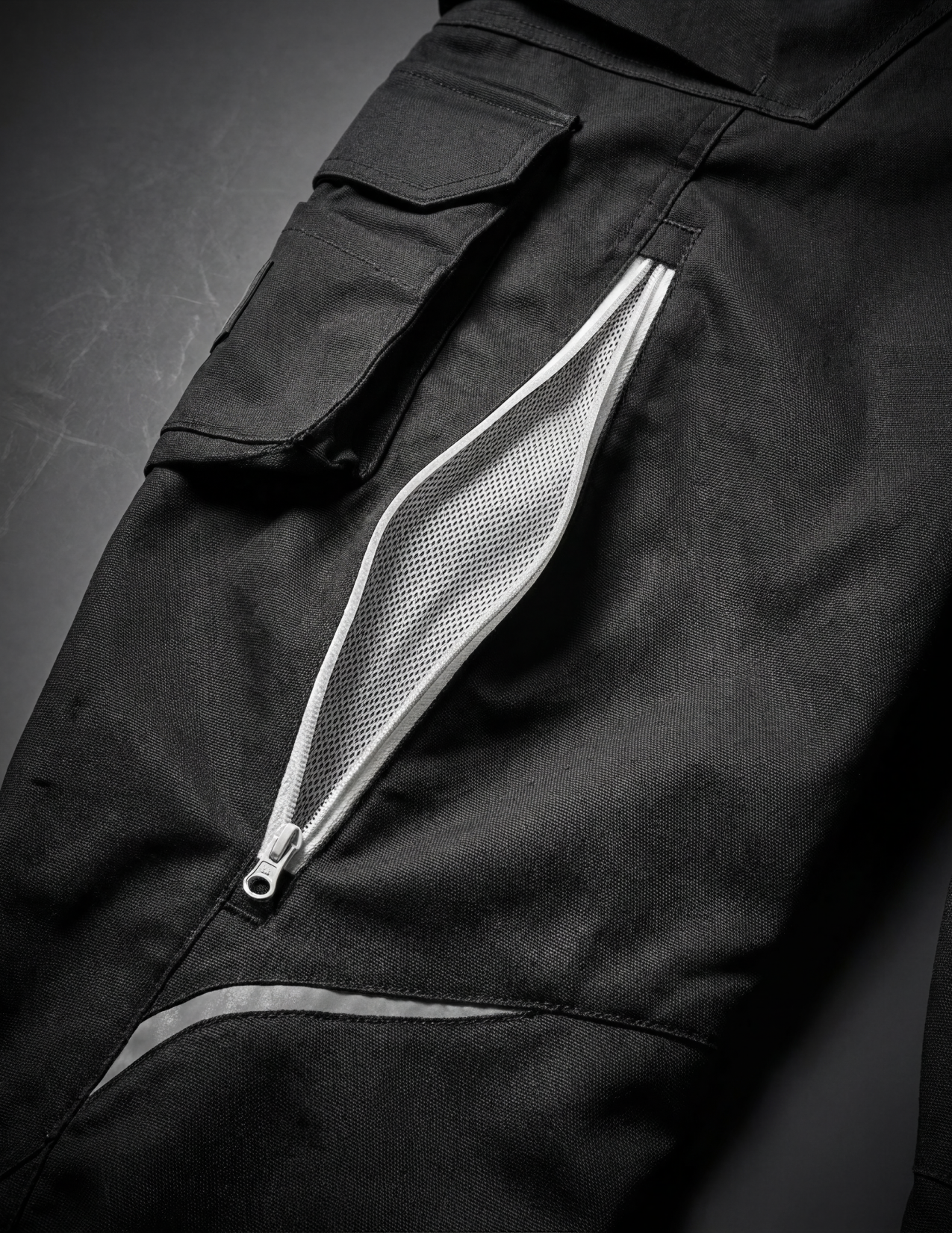 Close-up of black pants with a zipper pocket on a dark background