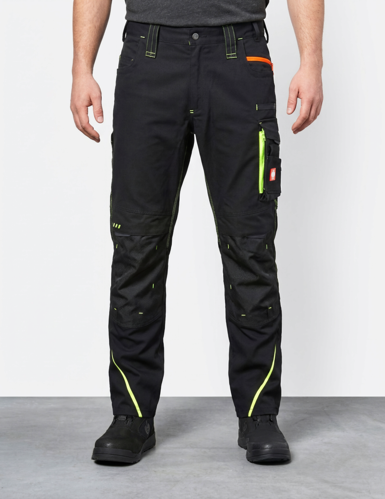 Person wearing black work pants with reflective accents on a plain background