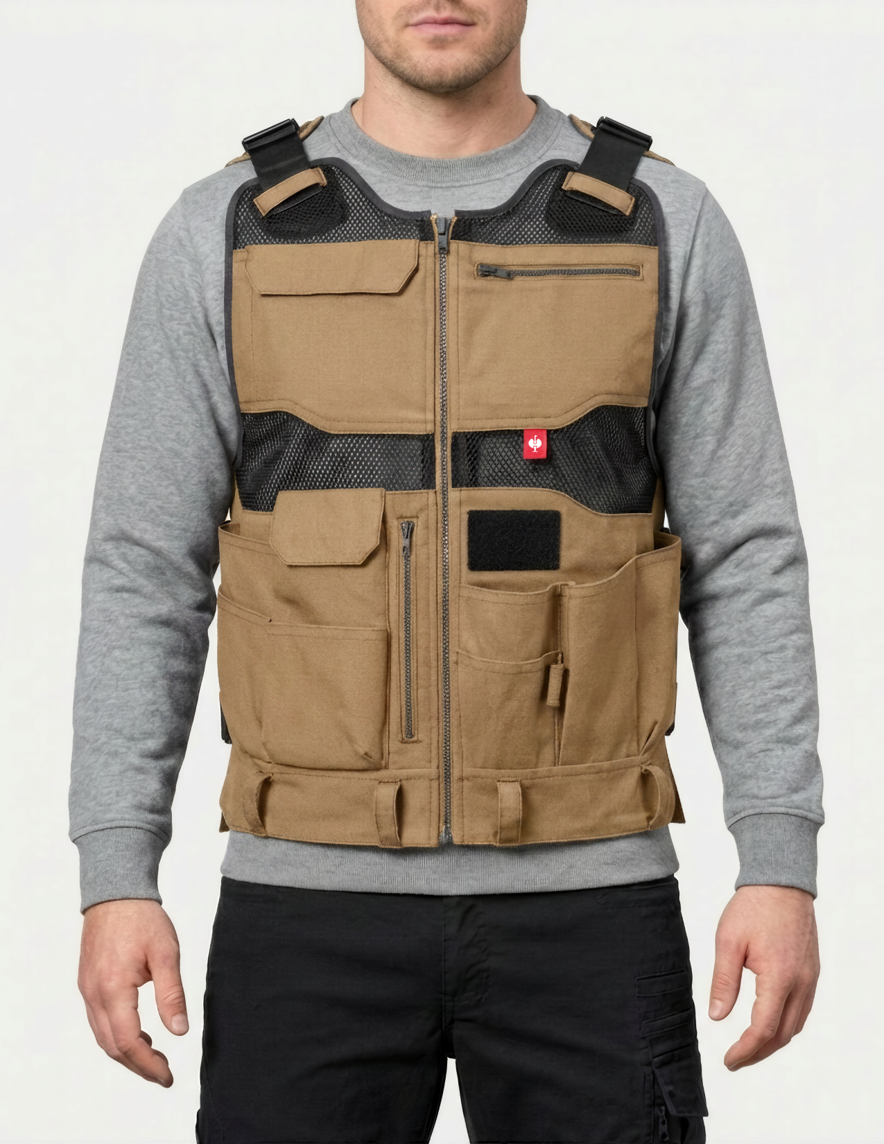 Person wearing a tan tool vest over a gray shirt on a white background