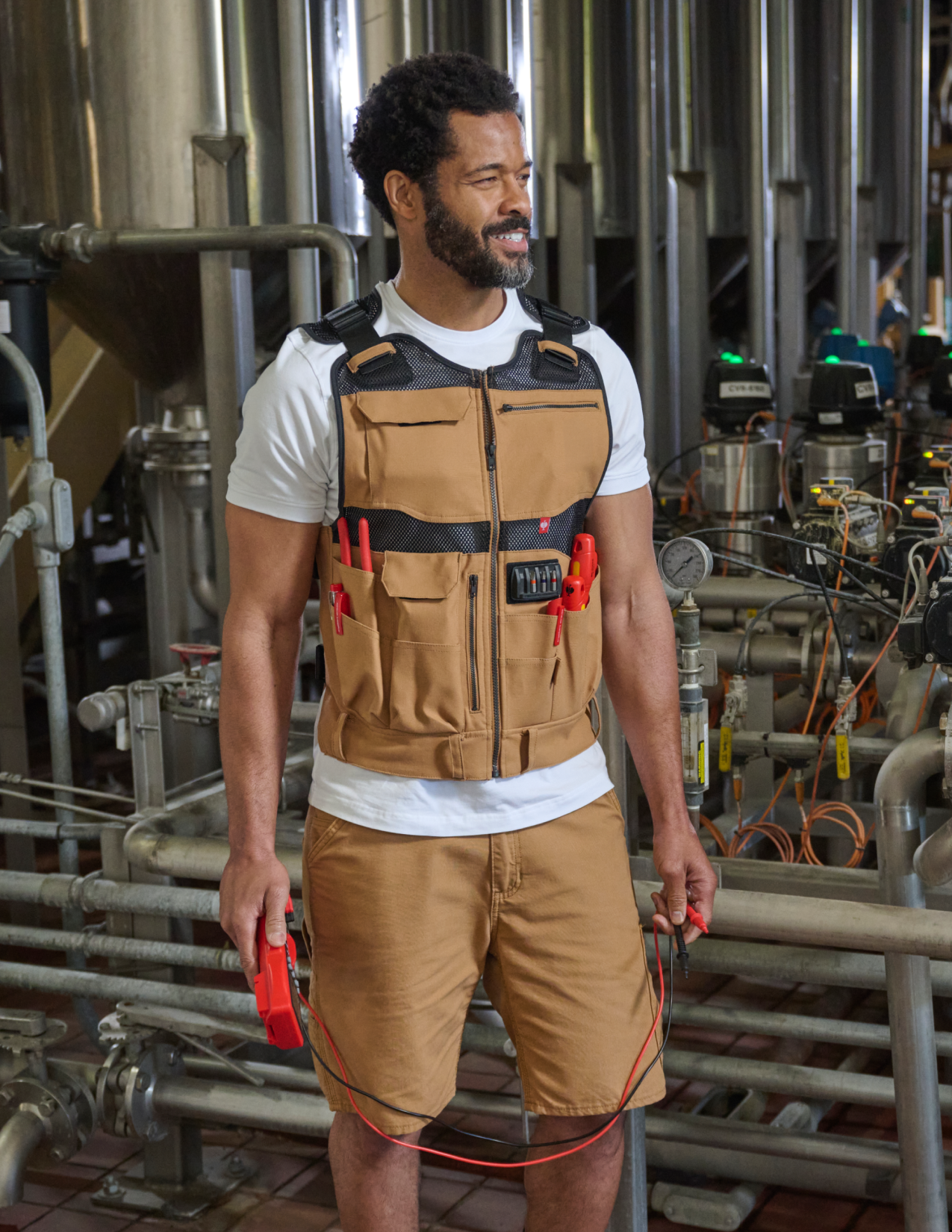 Man wearing a tool vest with equipment in an industrial setting