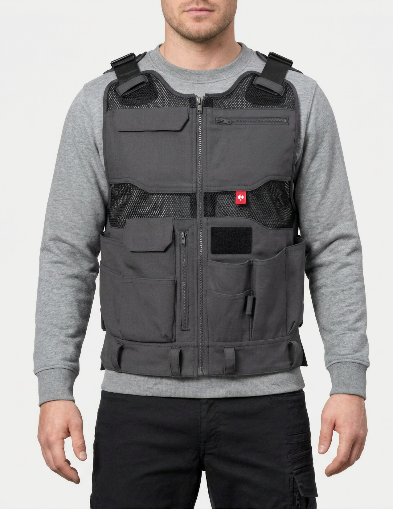 Person wearing a tool vest over a gray shirt on a white background