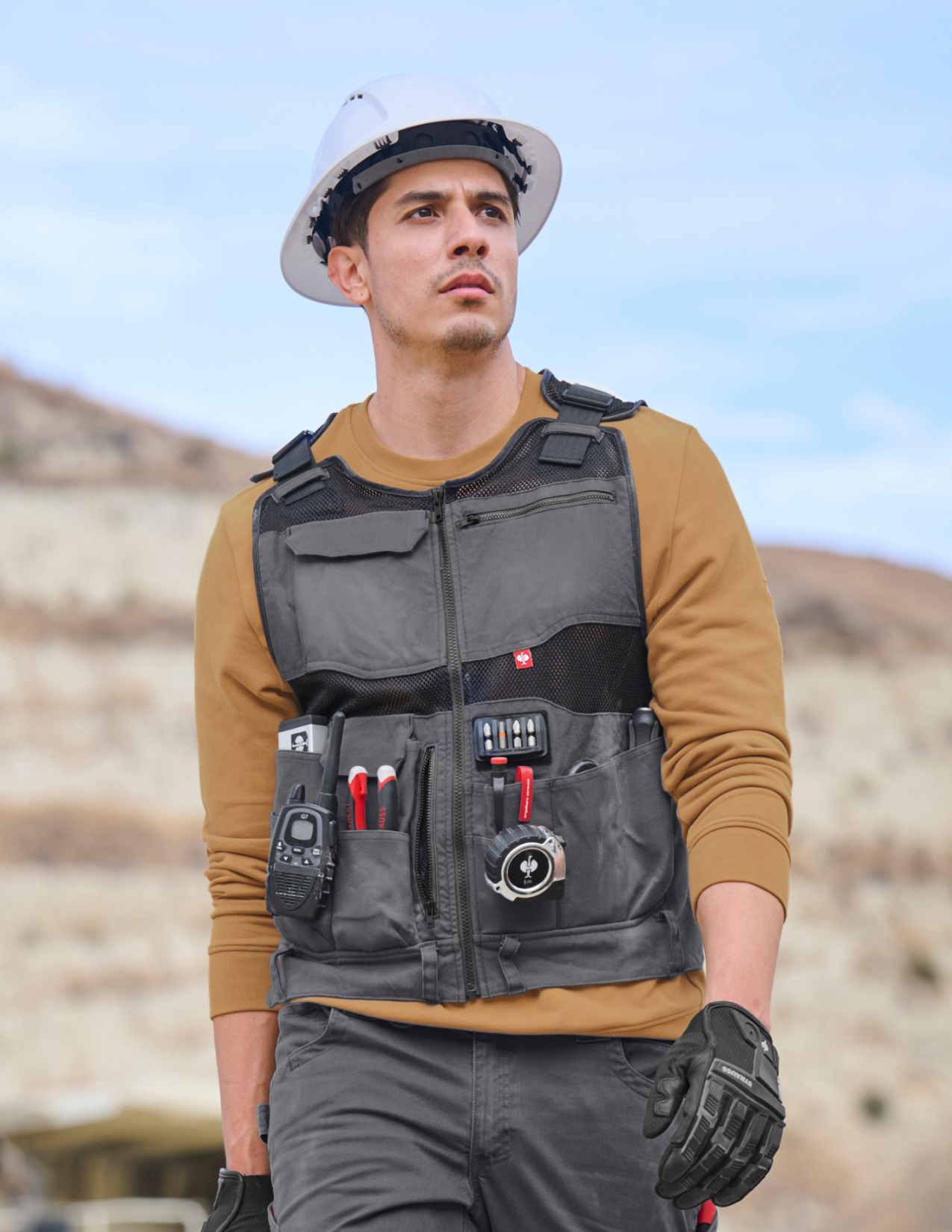 Person wearing a tactical vest with utility pouches in an outdoor setting